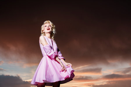 Woman in monroe dress on dramatic sky. Fashionable young model in style dress. Fashion woman in summer.の写真素材