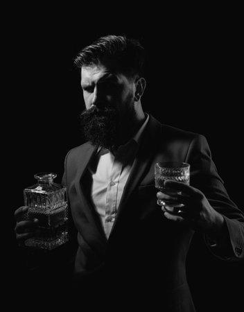 Bearded and glass of whiskey. Man Bartender with beard holds glass brandy. Alcohol concept.の写真素材