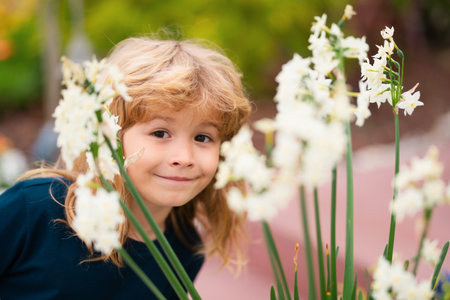 Outdoor small child boy portrait on the meadow. Little cute kid with flowers in a garden. Children play outdoors. Kid play outdoor. Spring kids portrait, funny face.の写真素材