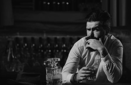 Portrait of a handsome bearded Businessman in elegant suit drinking a Whiskey.の写真素材