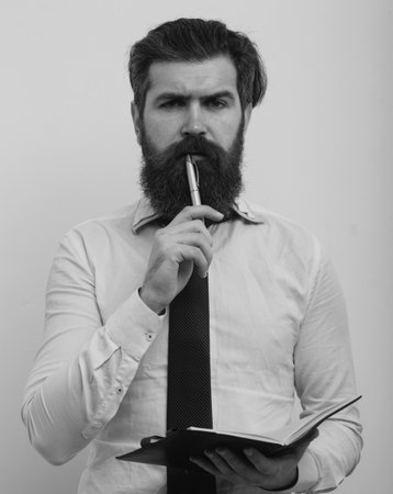 Handsome attractive business man having raised pen and notebook in hands, isolated on white background.の写真素材