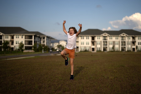 Excited kid boy running on green grass background, panoramic banner. Child running outdoor. Healthy sport activity for children. Little boy at athletics competition race. Runner kids exercising.の写真素材