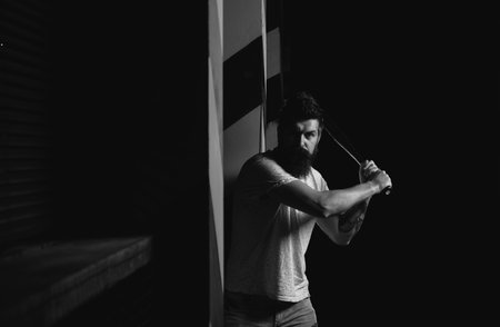 Aggression or anger and violence concept. Attack concept. Man unshaven face hold baseball bat. energy and fashion. Strong temper. Bearded man hold baseball bat. Ready to swing.の写真素材