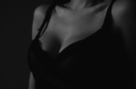 Lingerie concept. Sexy breas, boobs in bra, sensual tits. Beauty slim female body. Closeup of sexy girl boob in black bra.の写真素材