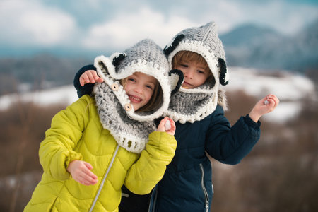 Little girl and boy enjoying winter playing in the winter forest. Children siblings having fun and hugging in beautiful winter park. Happy childhood.の写真素材