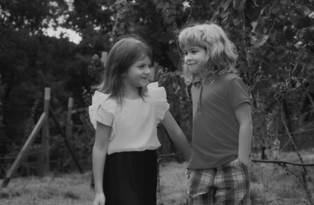 Cute little children playing outdoors. Portrait of two happy young kids at the spring park. Cute lovely boy and girl in backyard. Sister and brother walking in garden.の写真素材
