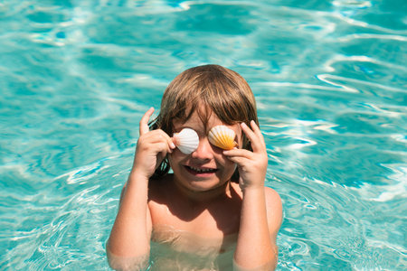 Child in swimming pool playing in water. Vacation and traveling with kids. Children play outdoors in summer. Covered eyes with shells.の写真素材