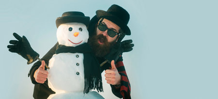 Merry christmas and happy new year. Funny winter snow man in hat play with snowman outdoor. Man with...