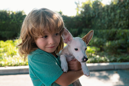 Portrait of a child boy plays with a dog outdoor. Child lovingly embraces his pet dog.の写真素材