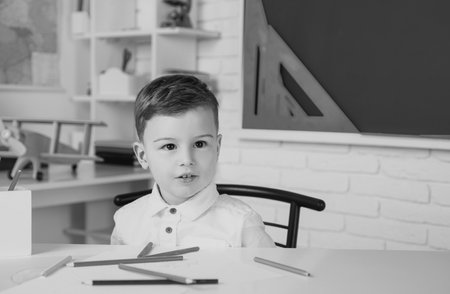 Elementary school kids in school. Cute child is sitting at a desk indoors.の写真素材