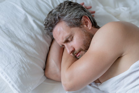 Man sleep in white bed. Sexy shirtless man sleep in bed at bedroom. Hispanic mature man sleeps at...