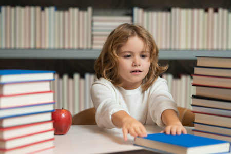 Back to school. School kid pupil studying in school library. Child reading book in library on bookshelf background.の写真素材