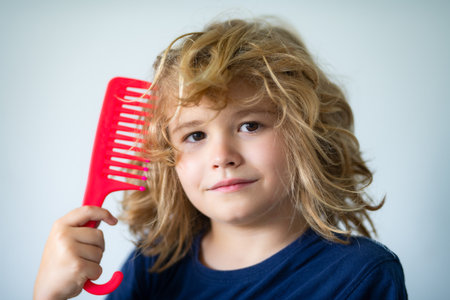 Kids barber shop. Child with brush combing hair. Boy taking hairstyle. Child brushing hair with comb, kids haircare.の写真素材
