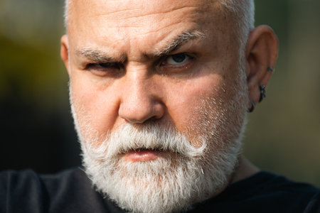 Close up portrait of serious expression 60 year old elder senior man. Mature man with serious...