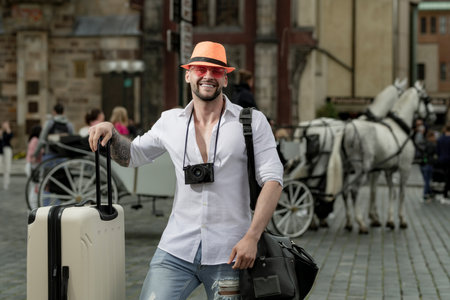 Tourist on holiday. Male traveler with suitcase outdoor. Portrait of young caucasian man in hat and sunglasses on summer vacation.の写真素材