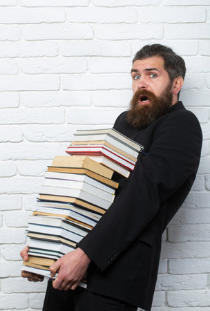 Portrait of a funny teacher or professor with book stack. Thinking serious mature teacher. Mature professor, middle aged teacher, bearded fun man. Falling books concept.の写真素材