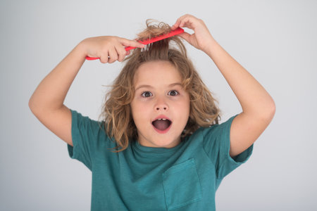 Child combing hair after shower. Child with curly hair hold hairbrush or comb. Healthy hair. Kid brushing unruly tangled hair.の写真素材