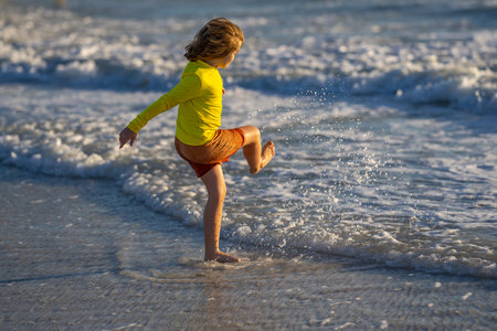 Kid running on beach having fun on summer holidays. Happy kids playing on sea. Children in nature with sea. Happy kids on vacations at seaside running in the water. Child running walking at beach.の写真素材