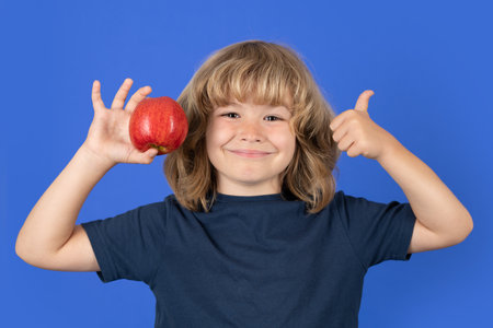 Little boy holding apple with fynny face. Kid eats healthy food.の写真素材
