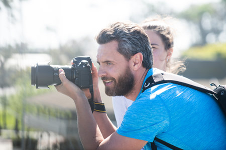 Man photographer with a large professional camera. Portrait of photographer with camera outdoor....