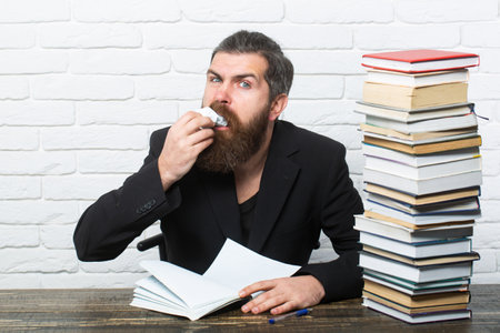 Portrait of a funny teacher or professor with book stack. Thinking serious mature teacher. Mature professor, middle aged teacher, bearded fun man.の写真素材