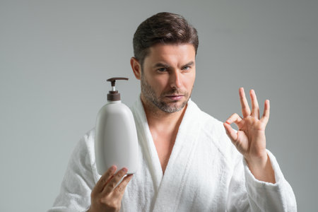 Man with bottle with dispenser pump for liquid soap, gel or foam. Cosmetic beauty products. Beauty man with cosmetic bottle. Natural cosmetics cream for skin care. Spa beauty products.の写真素材