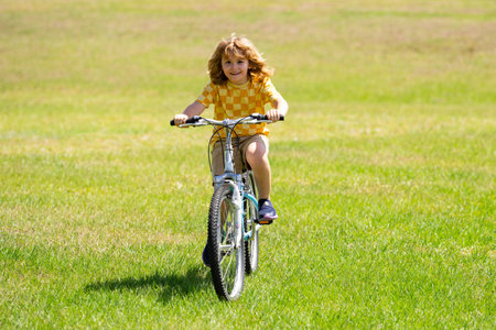 Little kid boy ride a bike in the park. Kid cycling on bicycle. Happy smiling child riding a bike....