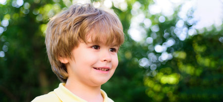 Close up portrait of cute child outdoors. Spring banner for website header. Portrait of little boy. Concept of kids face close-up. Head shoot children portrait in summer nature park.の写真素材