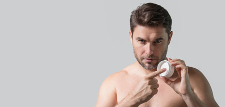 Cream for male skin. Banner of beauty man hold bottle with dispenser pump for liquid soap, gel or foam. Natural cosmetics cream for man. Spa beauty products. Man advertising new cosmetic product.の写真素材