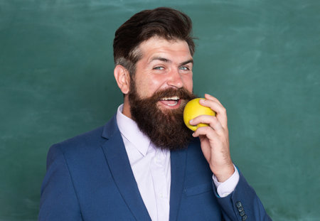 Portrait of a funny teacher or professor near blackboard. Thinking serious mature teacher. Mature professor, middle aged teacher, bearded man.の写真素材