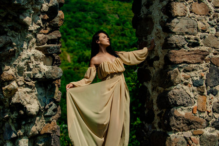 Woman, fashion model on fortress, old castle stones wall. Girl in a fashion dress outdoor.の写真素材