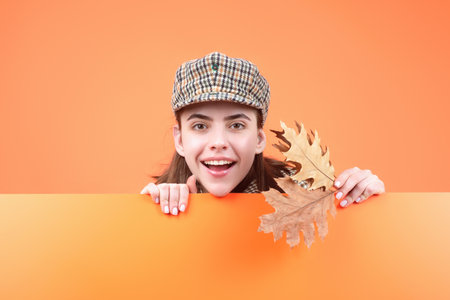 Beautiful woman in autumn clothes hold falling leaves posing in studio. Gorgeous brunette model girl with yellow autumn maple leaf. Autumn woman in studio. Autumnal mood.の写真素材