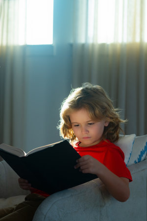 School boy with book. Kids and literature. Child reading book, sitting at home in cozy living room...