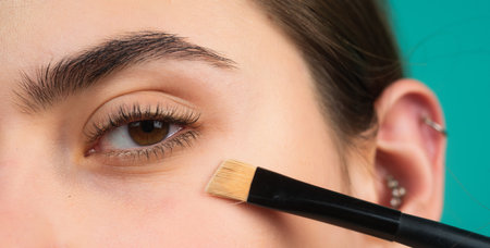 Perfect eyebrow. Close up of woman getting eyebrow make-up. Macro applying cosmetics on her eyebrow with brush. Perfect shape of eyebrow, brown eyeshadows and long eyelashes. Shape eyebrows.の写真素材