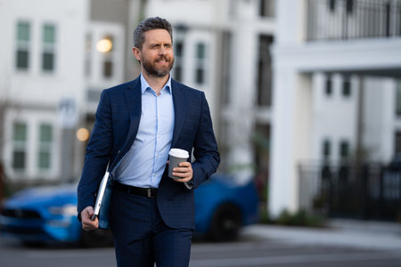 Portrait of a confident business man walking in city. Bandsome business man in casual suit walking at street. Business man walking in formal suit. Attractive middle aged business man walking outdoor.