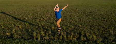 Sporty kid boy running on green grass background, panoramic banner. Child running outdoor. Healthy sport activity for children. Little boy at athletics competition race. Runner kids exercising.の写真素材