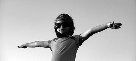 Kids with pilot goggles and helmet playing with vintage wooden airplane outdoors. Portrait of children against summer sky. Travel and freedom concept.の写真素材