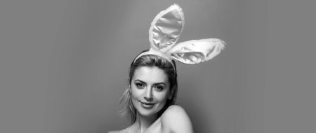 Easter banner with bunny woman. Easter bunny woman. Studio shot of a young woman wearing bunny ears.の写真素材
