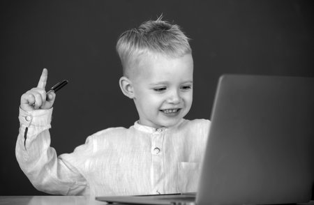 Cute excited school kid boy study in a classroom. Genius child programming, computer training.の写真素材