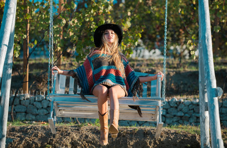 Young woman on swing relax at nature garden. Woman resting in summer holiday. Beautiful hipster woman breathing on a white wooden swing.の写真素材