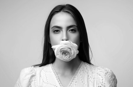 Rose flowers in a mouth. Beauty romantic woman with rose flowers. Valentines Day design. Pink rose in sensual sexy womans mouth.の写真素材