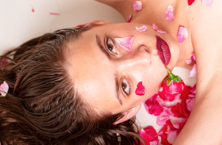Sensual woman on spring roses background. Seductive and sexy nature girl looking at camera. Perfect skin.の写真素材