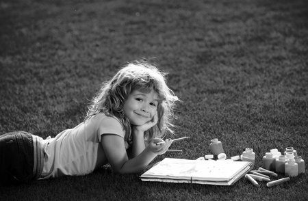 Young talented boy artist painter. Kids painting with paints color and brush in park outdoor.の写真素材