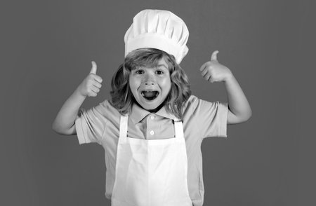 Excited funny chef cook. Child chef dressed cook baker apron and chef hat with thumbs up isolated on studio background.の写真素材