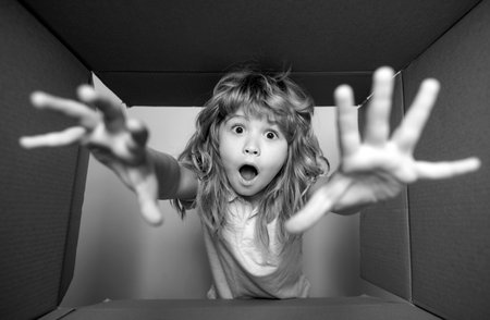 Surprised cute child opening a present. Cardboard boxes, parcels. Delivery service concept. Parcel packaging or unpacking concept.の写真素材