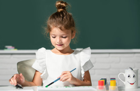 Little girls drawing a colorful pictures with pencil crayons in school classroom. Painting kids....