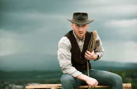Cowboy with lasso rope on sky background. Western man with cowboy hat.の写真素材