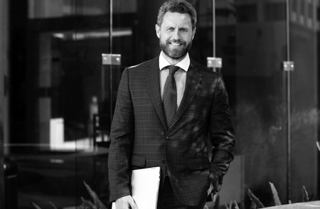 Busines sman standing outside a modern house. Real estate concept. Agent ready to sell home.の写真素材