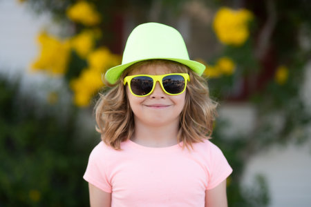 Summer kids in hat and sunglasses. Lifestyle portrait of funny kid outdoors. Summer kids outdoor portrait. Close up face of cute child. Kid having fun outdoor on sunny summer day.の写真素材