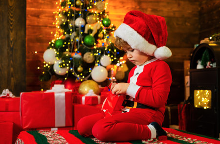 Happy little boy child with present or gift box indoors. Happy cute child in Santa hat with present have a Christmas.の写真素材